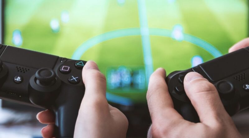 os personas jugando videojuego con mandos de PlayStation.